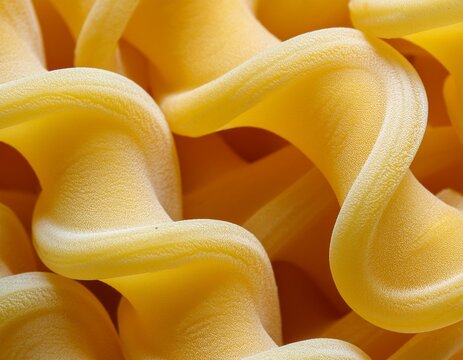 macro view of uncooked funghetti pasta with frilly curved edges and a mushroom like shape forming a textured yellow food background