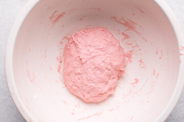Overhead view of strawberry sourdough in a white bowl, top view of pink bread dough being mixed in a bowl, high hydration bread dough in a mixing bowl