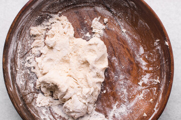 Overhead view of bread dough being mixed in a wooden bowl, top view of homemade bread dough in a...