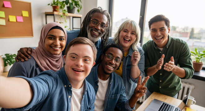 Young adult businessman with down syndrome taking selfie with multiethnic business team in bright inclusive workplace