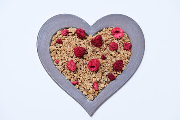 muesli with freeze-dried raspberries in a heart-shaped frame on a white background
