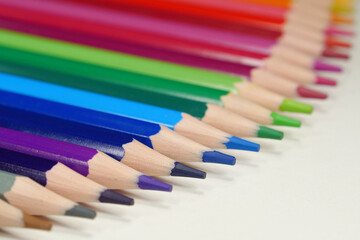 New wooden colored pencils of rainbow colors, perfectly sharpened, lie on table