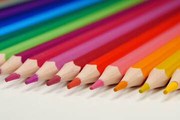 New wooden colored pencils of rainbow colors, perfectly sharpened, lie on table