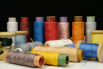 Spools with multi-colored threads on black background, close-up shot