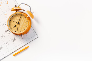 Alarm clock is on calendar with pencil, top view. Planning and time management concept