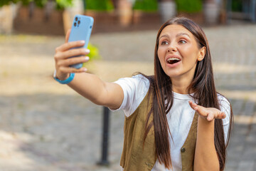 Caucasian young woman blogger taking selfie on smartphone, communicating video call online with...