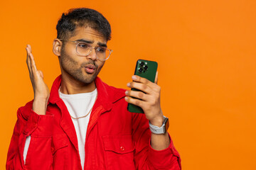 Upset sad Indian man use smartphone typing browsing, play game loses surprised by sudden lottery...