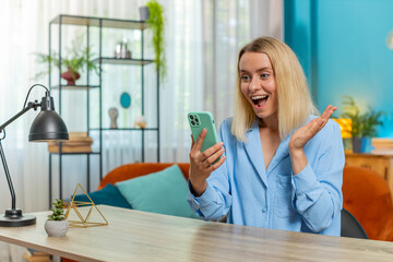 Young winner woman freelancer using mobile smartphone typing browsing say Wow yes found out great...