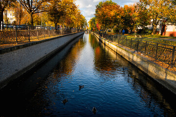 Beautiful autumn cityscape in Europe. Water in old canal and yellow leaves on the trees