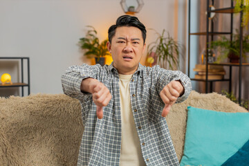 Dislike. Portrait of upset Chinese man showing thumbs down sign gesture, expressing discontent,...