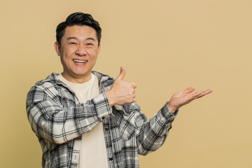Asian middle-aged man showing thumbs up and pointing right empty place, advertising area for...