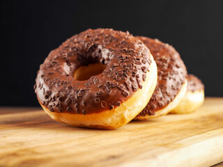 Sweet tasty chocolate donuts on wooden board. Popular desert and snack. Fine bakery product.