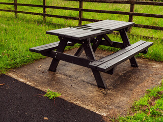 Sitting area with picnic spot on a table in a park. The surface is wet after a rain. Summer season theme. Nobody.