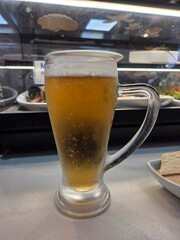 Refreshing cold beer glass in a restaurant setting. Vertical banner. Copy space. International Beer Day