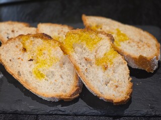 Freshly sliced artisan bread with olive oil on slate surface