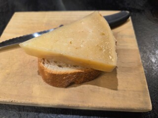 Gourmet cheese slice on bread with knife on wooden board. World Cheese Day. Spanish tapas