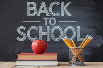An apple and pencils sit on books in front of a chalkboard that says back to school