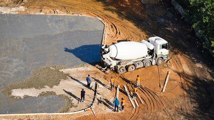 Aerial view of construction workers leveling freshly poured concrete at a construction site with a...