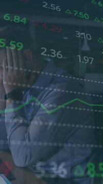 Animation of stock market data processing against stressed caucasian man working late at office