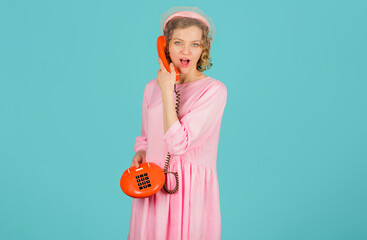 Beautiful young woman talking on vintage phone. Pin-up girl in pink dress and bonnet with veil...
