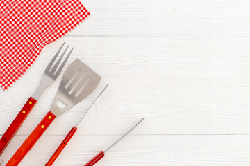 Set with barbecue utensils and equipment with red picnic napkin. Stainless steel tools. Top view