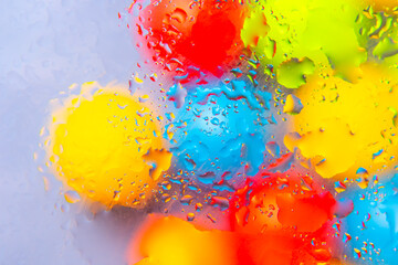 Vibrant abstract composition of water drops in red, yellow, blue, and green hues on a glossy...