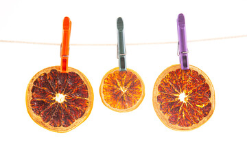 dried pieces of different citrus fruits hang on colored clothespins