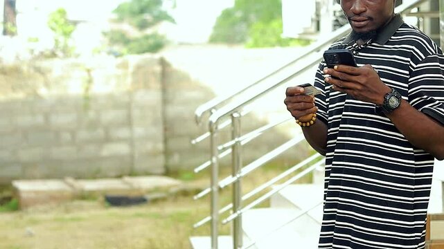 copy space video of young black man standing using mobile phone and bank card