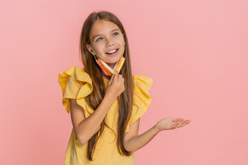 Little child girl fearfully shows a stop gesture while wearing a medical mask, then removes it and...