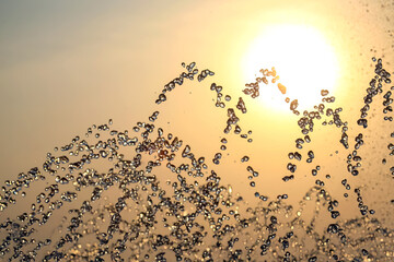 silhouettes of drops falling water fountain against the backdrop of the setting sun