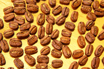 A collection of roasted coffee beans shaped into an oval on a shiny gold background, showcasing...
