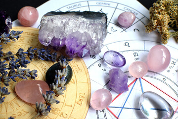 Beautiful crystals of amethyst and rose quartz and dried lavender herbs with symbols of the zodiac...