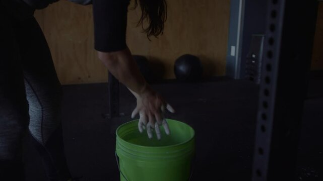 Woman performs hanging leg raises after chalking her hands for grip
