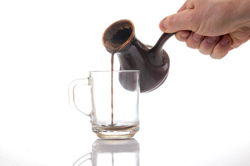 Rich coffee flows from a vintage ceramic pot into a clear glass cup, with a striking pour and...