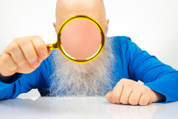 man hides his face with a magnifying glass. The concept of searching for a person in a database. Look at the world incognito. anonymous behind the curtain