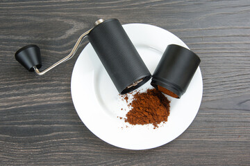 Detailed view of a manual coffee grinder, split to reveal freshly ground coffee, with a small spill...