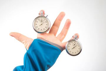Two mechanical stopwatches hang on the fingers of a male hand. Time part precision. Measurement of...