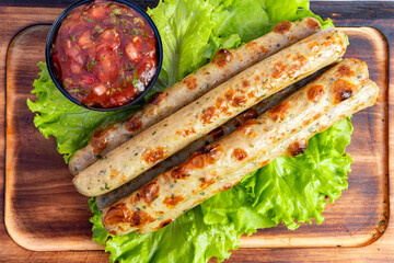 Grilled sausage links served with fresh salsa on a bed of lettuce at an outdoor picnic