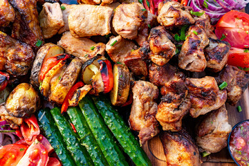 Grilled meats and vegetables on a wooden platter at a summer gathering