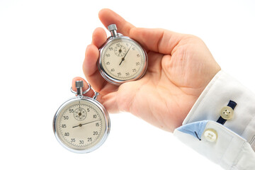 Two mechanical stopwatches hang on the fingers of a male hand. Time part precision. Measurement of...