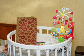 Nursery setup with colorful mobile and decorative bag beside a crib in a cozy room