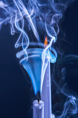 Smoke from an extinguished candle on a dark background. The concept of spirituality and the end of...