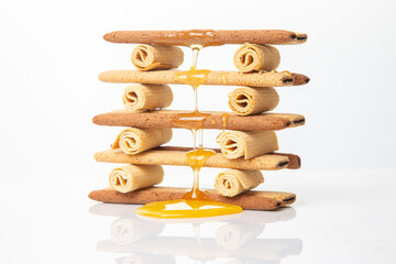 Fresh flower honey flows and drips onto herdry crispy cookie sticks. Dessert snack food.