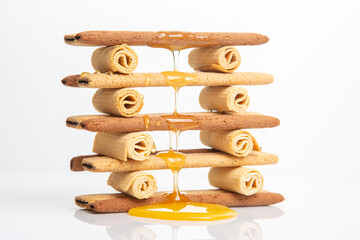 Fresh flower honey flows and drips onto herdry crispy cookie sticks. Dessert snack food.