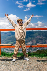 Happy Colombian boy raising arms in a sunny outdoor mountain scene