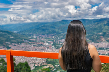 Young Colombian woman admiring cityscape of Medellin from mountain viewpoint