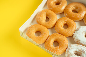 A variety of colorful donuts arranged in a box, featuring a mixture of glaze, and powdered sugar. Perfect for recipes, articles or any cooking content