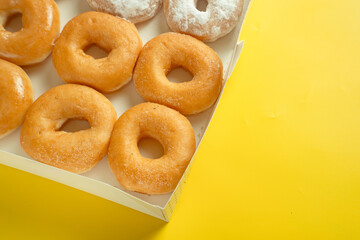 A variety of colorful donuts arranged in a box, featuring a mixture of glaze, and powdered sugar....