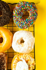 A close-up shot of a variety of donuts on a cooling rack. The donuts are topped with colorful...