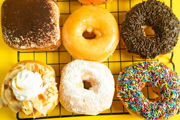 A close-up shot of a variety of donuts on a cooling rack. The donuts are topped with colorful...